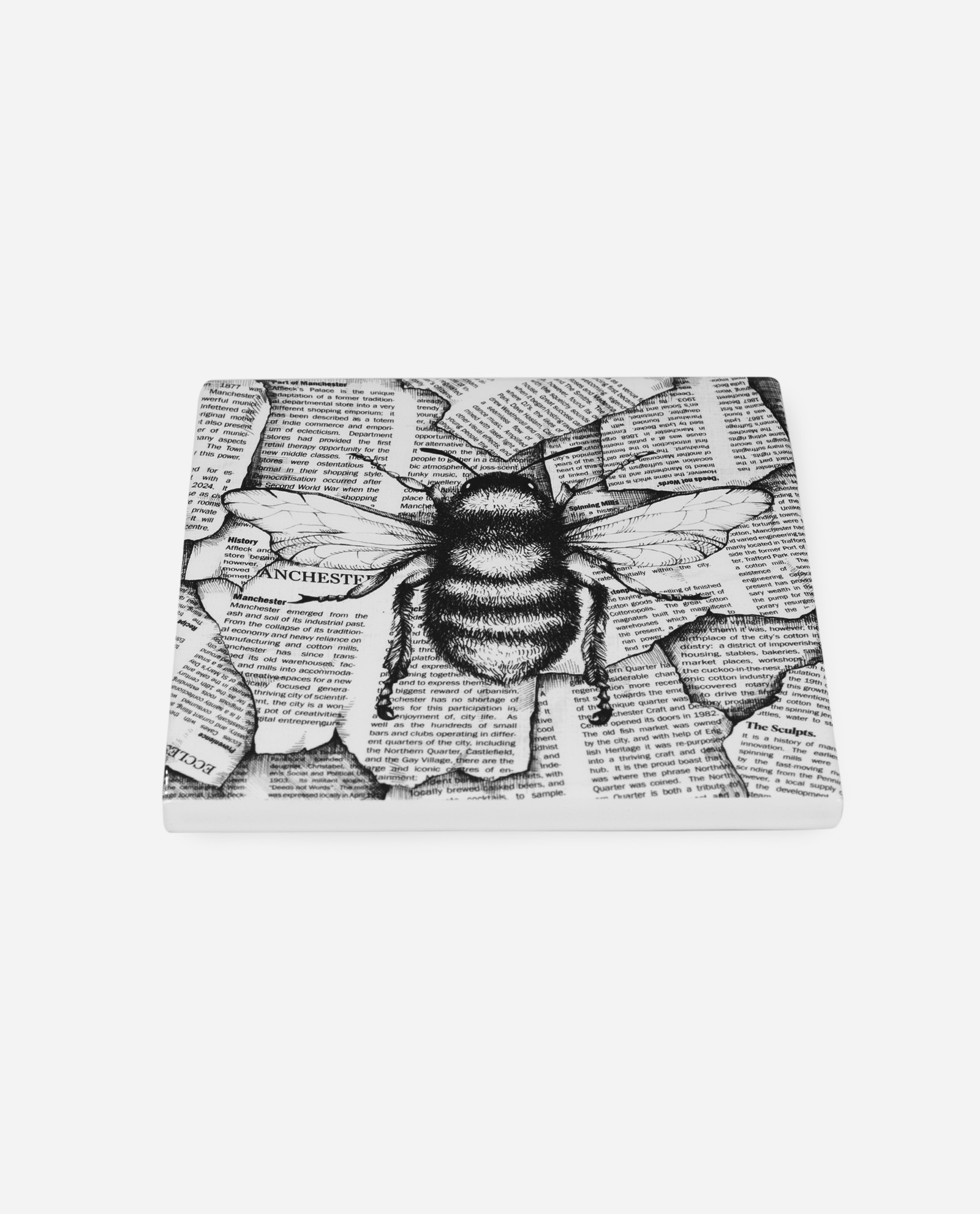 Angled view of ceramic Manchester bee tile showing dimensional glazed surface and newspaper collage detail by The Sculpts