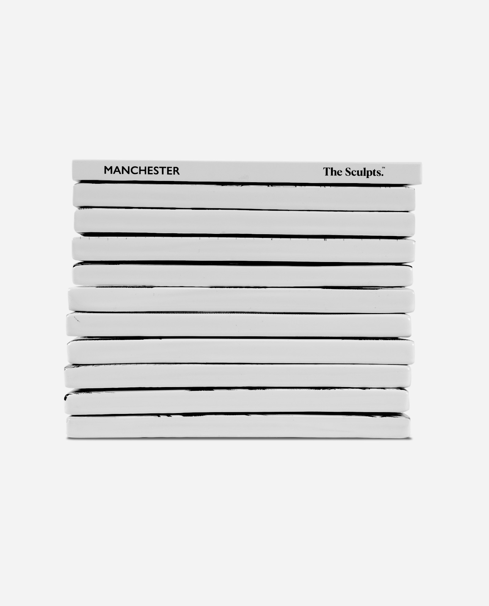 Manchester Tile Set side view showing stack of ten white ceramic tiles with MANCHESTER text and The Sculpts branding on spine